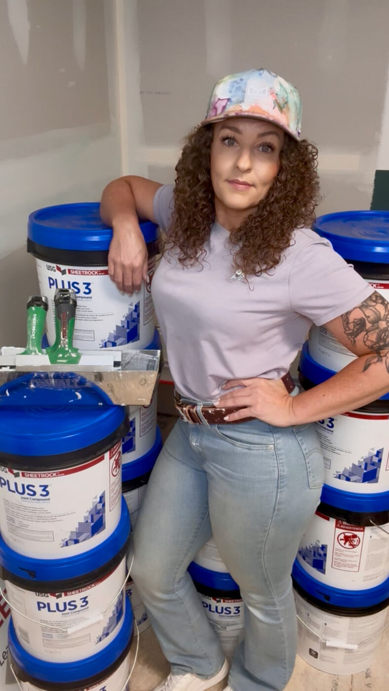Lydia leaning on stacked buckets of joint compound