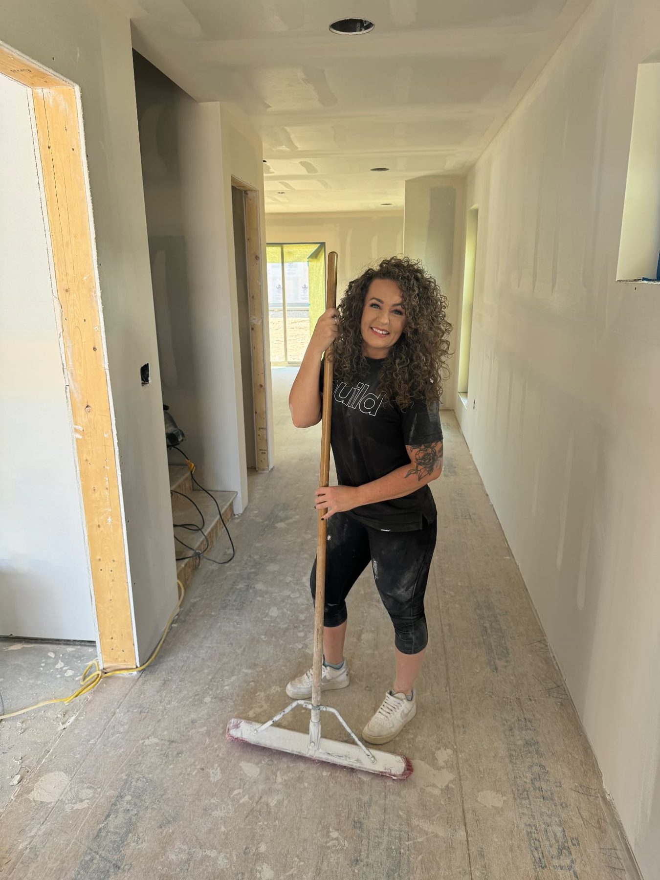 Lydia sweeping up on a drywall jobsite